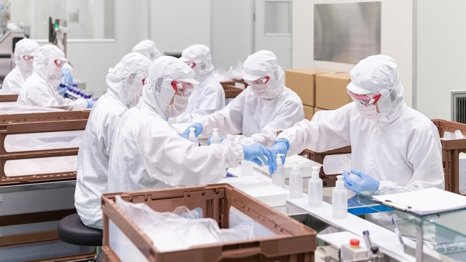 Kormesic Southeast Asia skincare OEM facility showing technicians in full cleanroom suits packaging cosmetic bottles