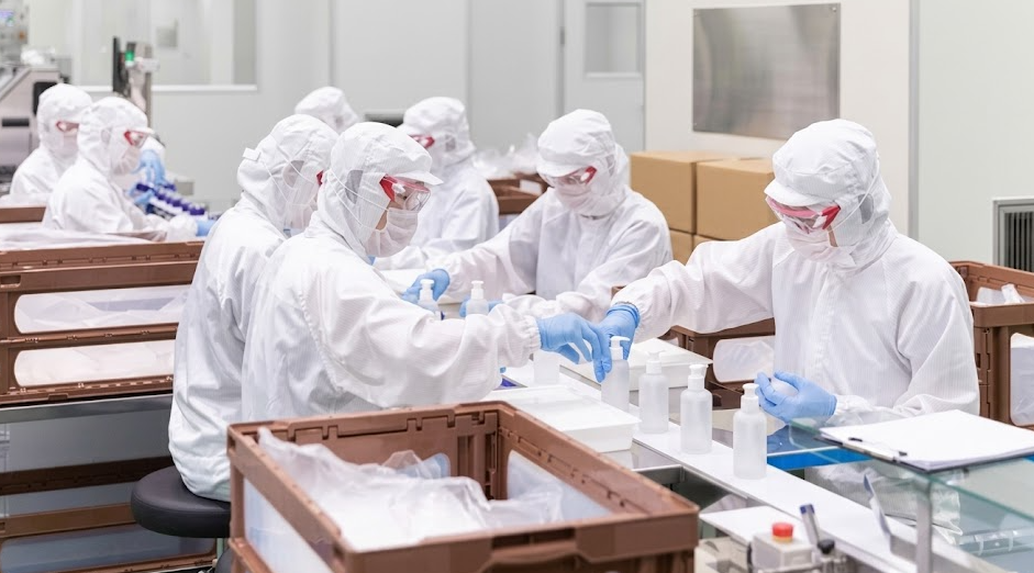 Kormesic Southeast Asia skincare OEM facility showing technicians in full cleanroom suits packaging cosmetic bottles